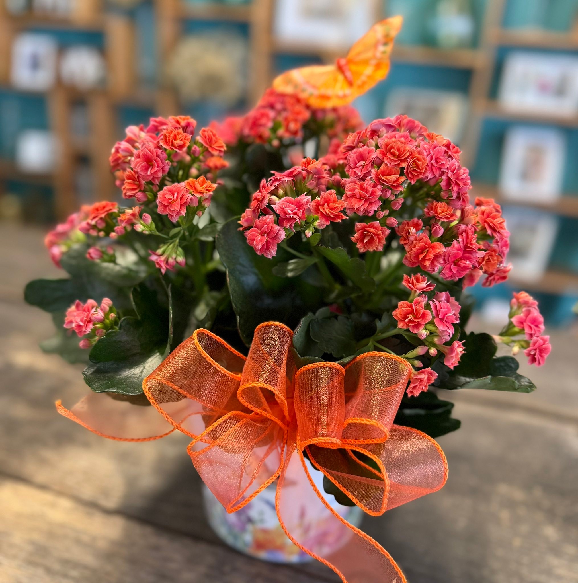 Bouquet of pink and coral flowers with an orange ribbon bow, indoors.